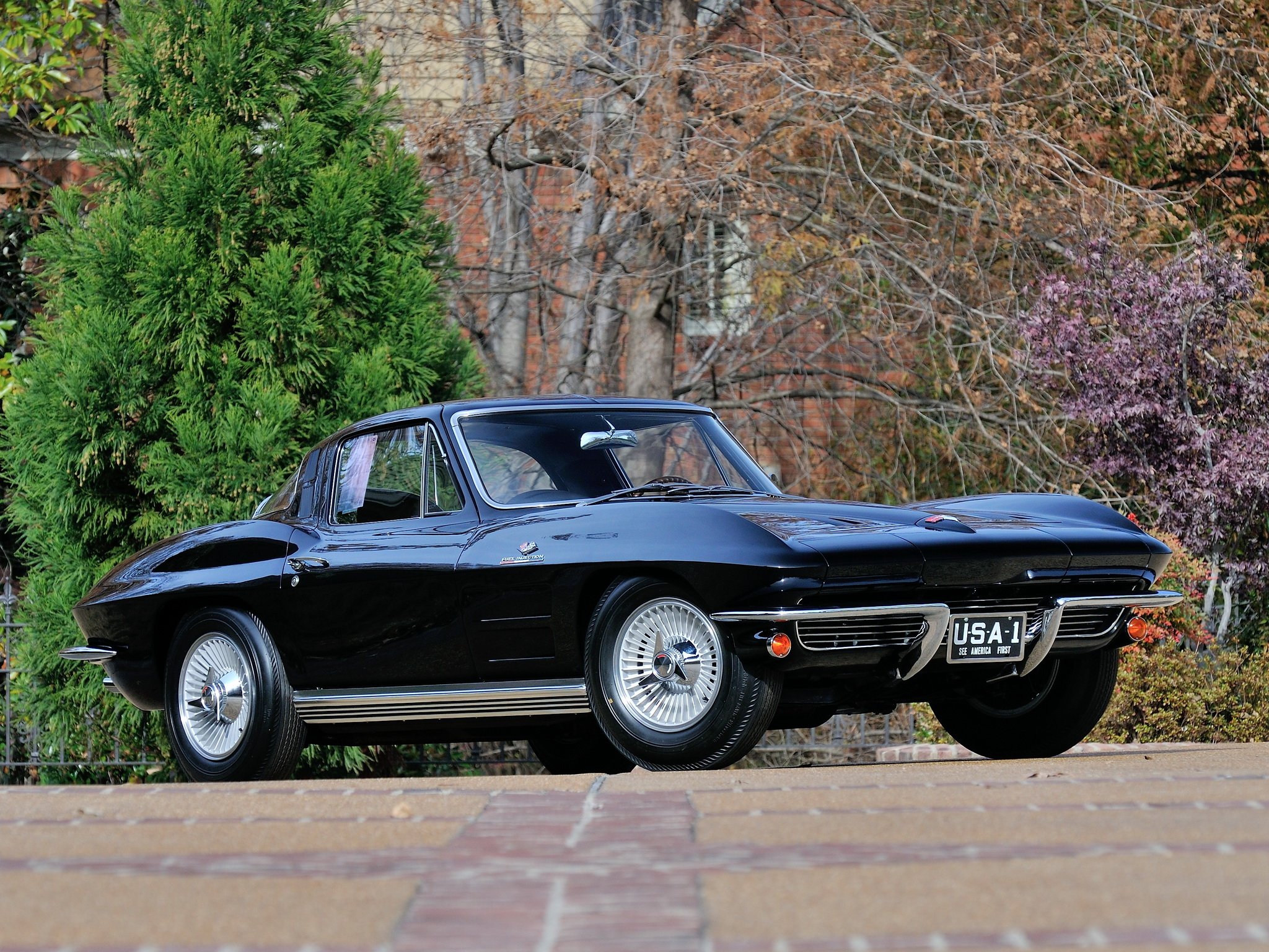 Black 1964 L84 Stingray Corvette on road with trees in background