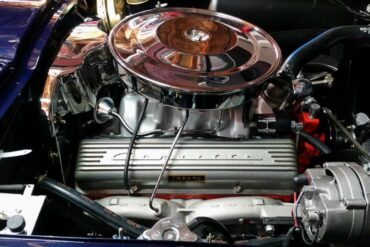 Exposed 1964 L76 engine sitting in blue Corvette with hood open