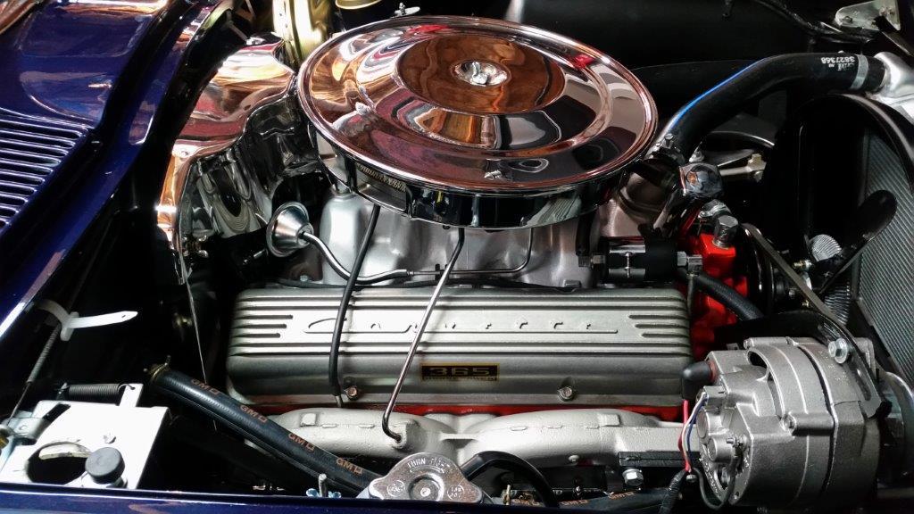 Exposed 1964 L76 engine sitting in blue Corvette with hood open