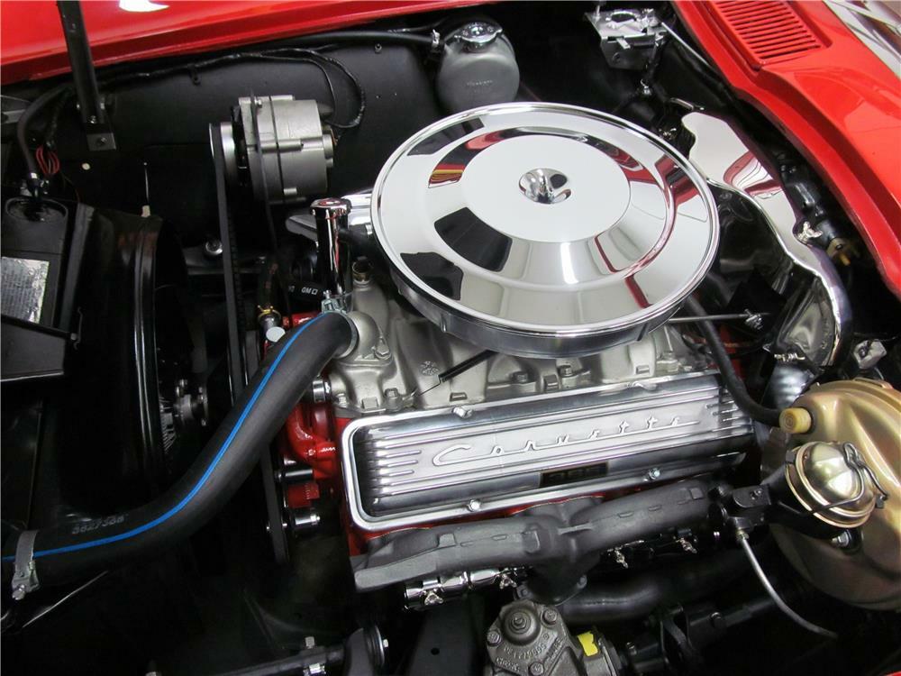 Close-up of 1964 L76 engine sitting in open hood of red Corvette