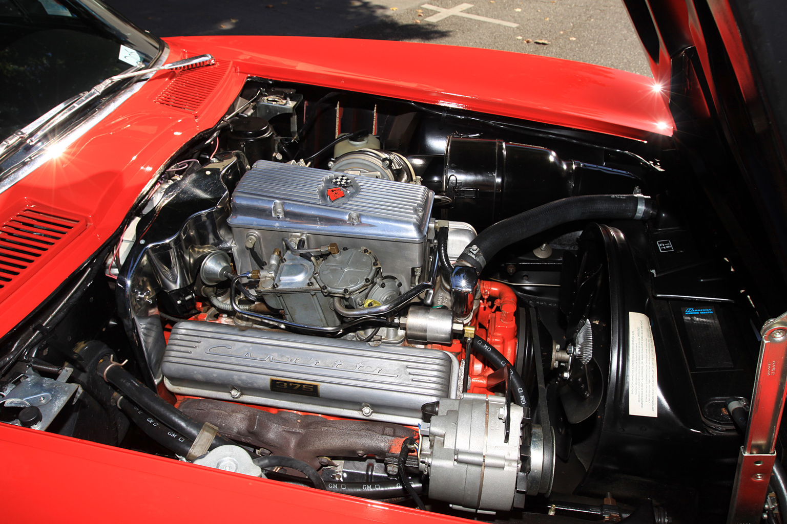 Exposed 1964 L84 engine sitting in red Corvette with hood up