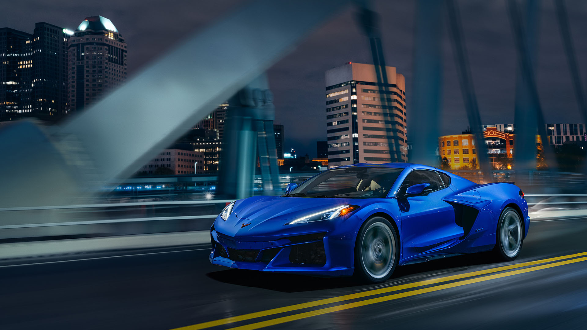 blue Corvette E-Ray driving through a bridge at night.