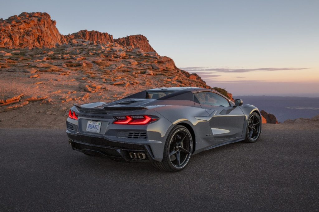 Rear 3/4 view of a 2024 Corvette E-Ray 3LZ convertible in Sea Wolf Gray Tricoat parked on a mountain road. Pre-production model shown. Actual production model may vary. Model year 2024 Corvette E-Ray available 2023. (Image courtesy of Chevrolet Press Room.)