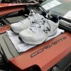 White New Balance sneakers on top of a Corvette engine