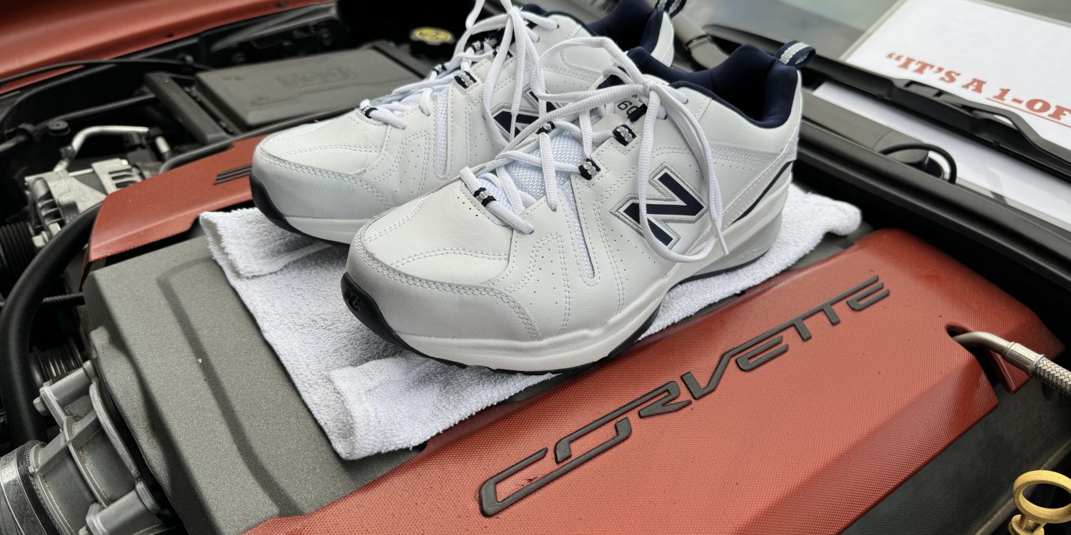 White New Balance sneakers on top of a Corvette engine