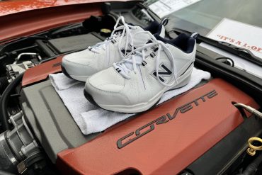 White New Balance sneakers on top of a Corvette engine