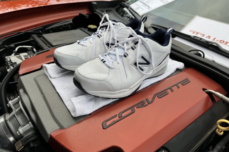 White New Balance sneakers on top of a Corvette engine