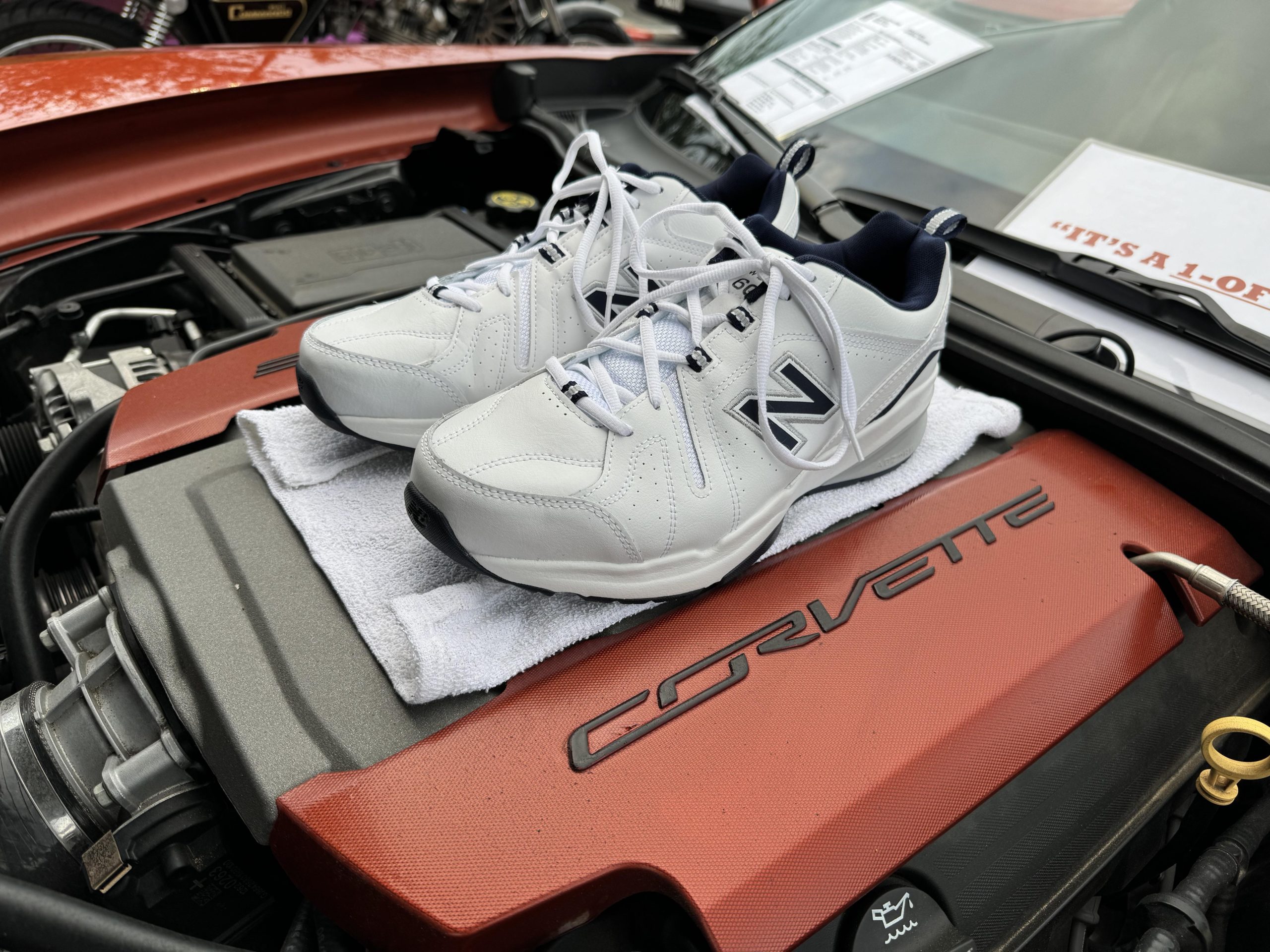 White New Balance sneakers on top of a Corvette engine
