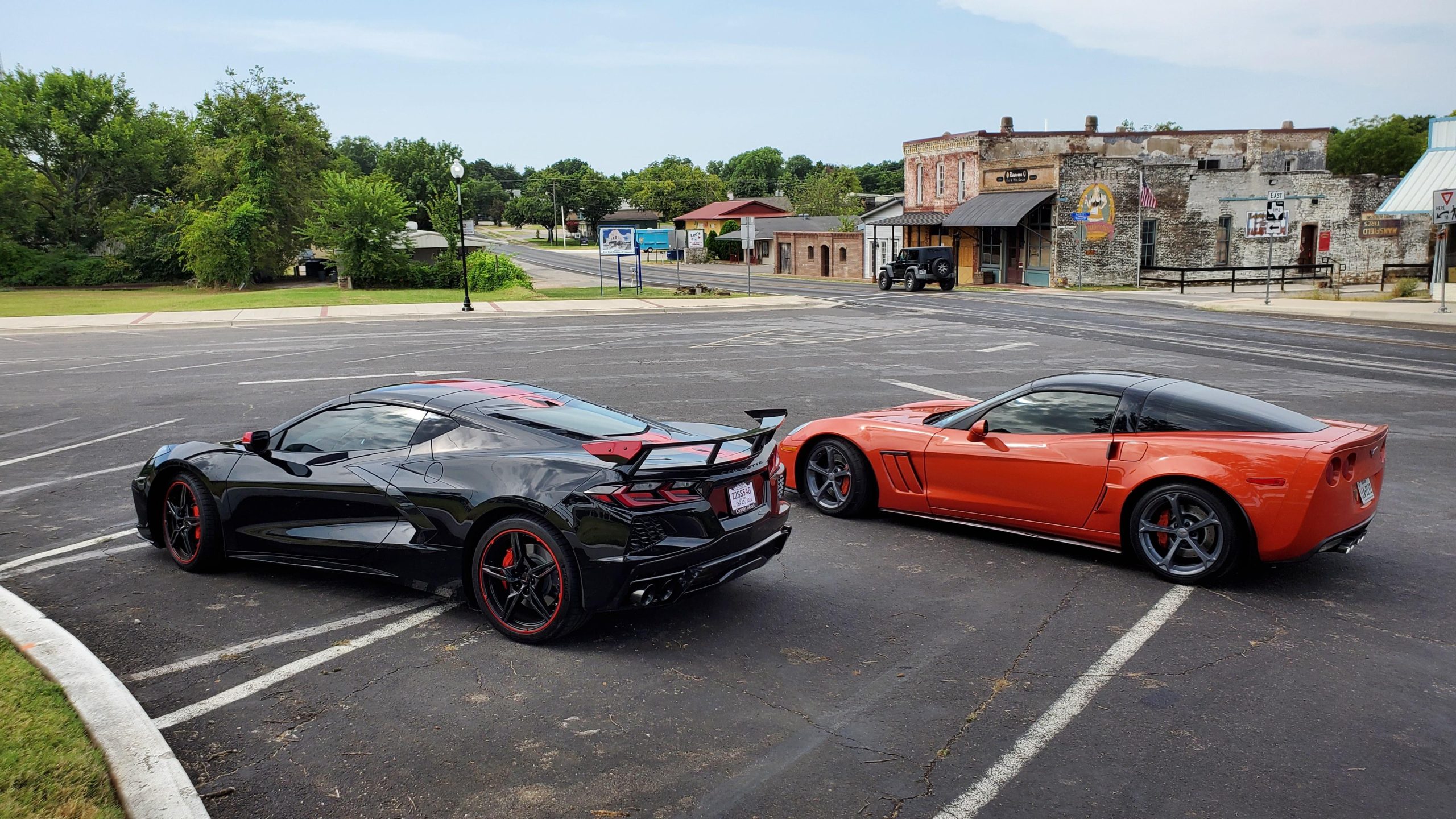 Black C8 Corvette and orange C6 Corvette on a parking lot