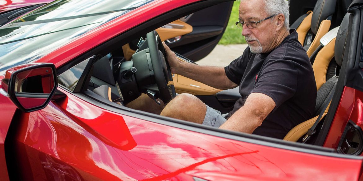 Old guy getting inside a red C8 Corvette convertible
