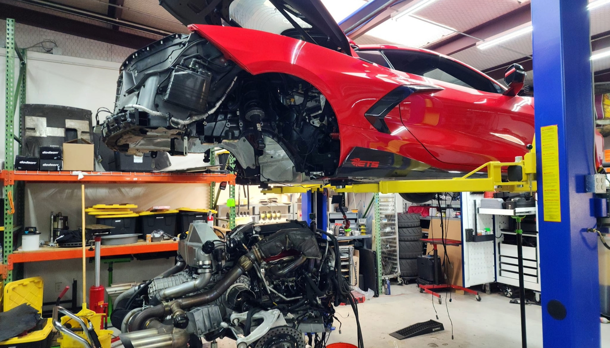 Red C8 Corvette on a lift at a repair shop